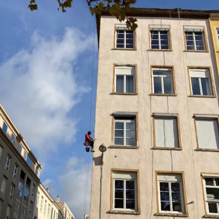 Cordiste suspendu sur cordes pour la réfection d'enduit de la façade d'un immeuble