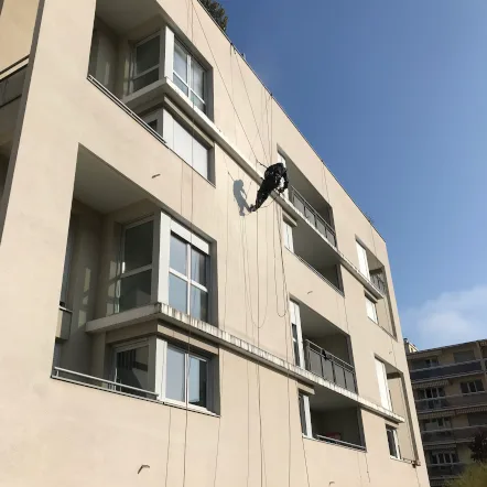 Technicien cordiste intervenant sur la façade d'un immeuble à Montpellier